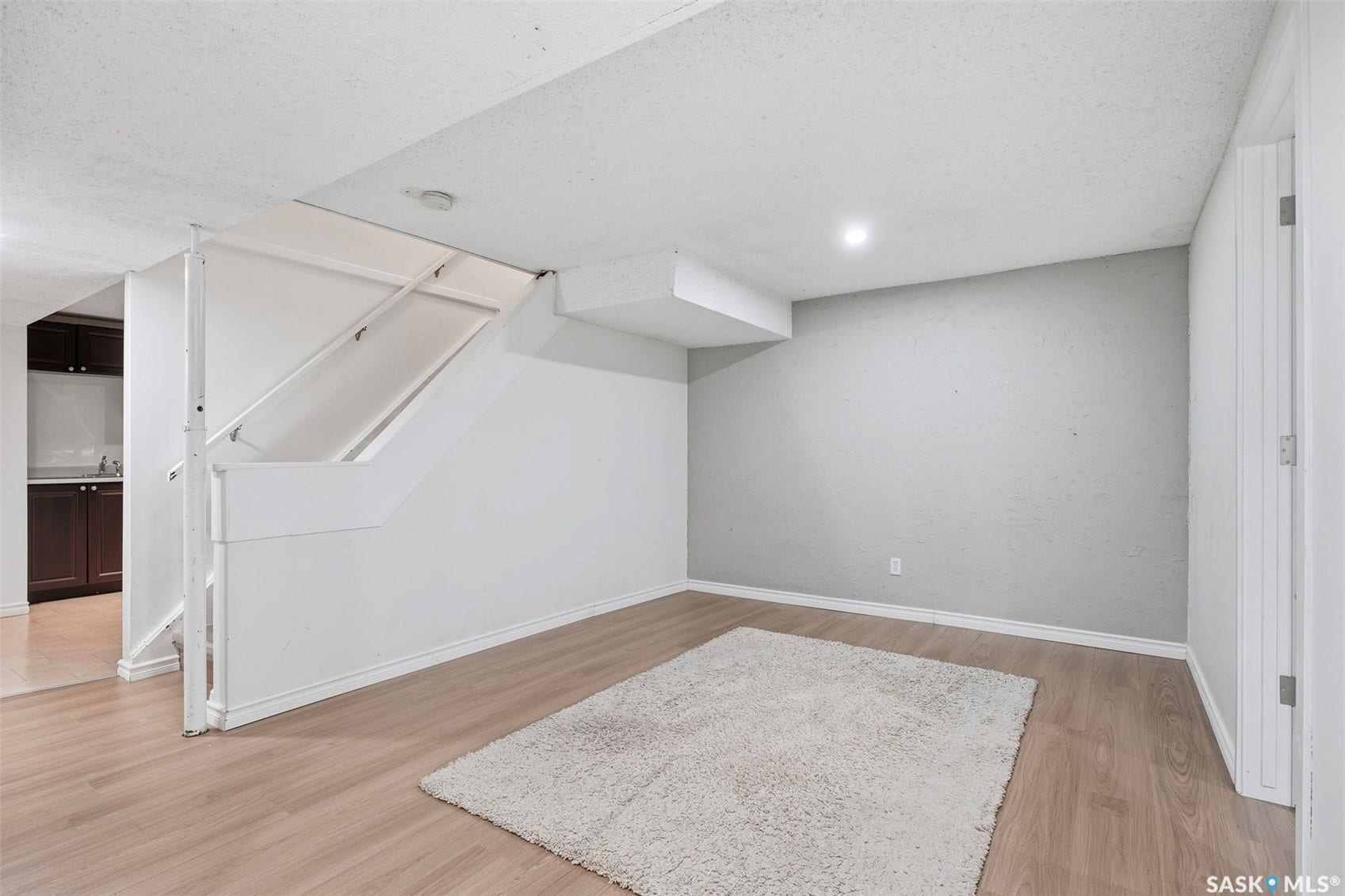 Wood-finish flooring, recessed lighting, and a white painted stairway
