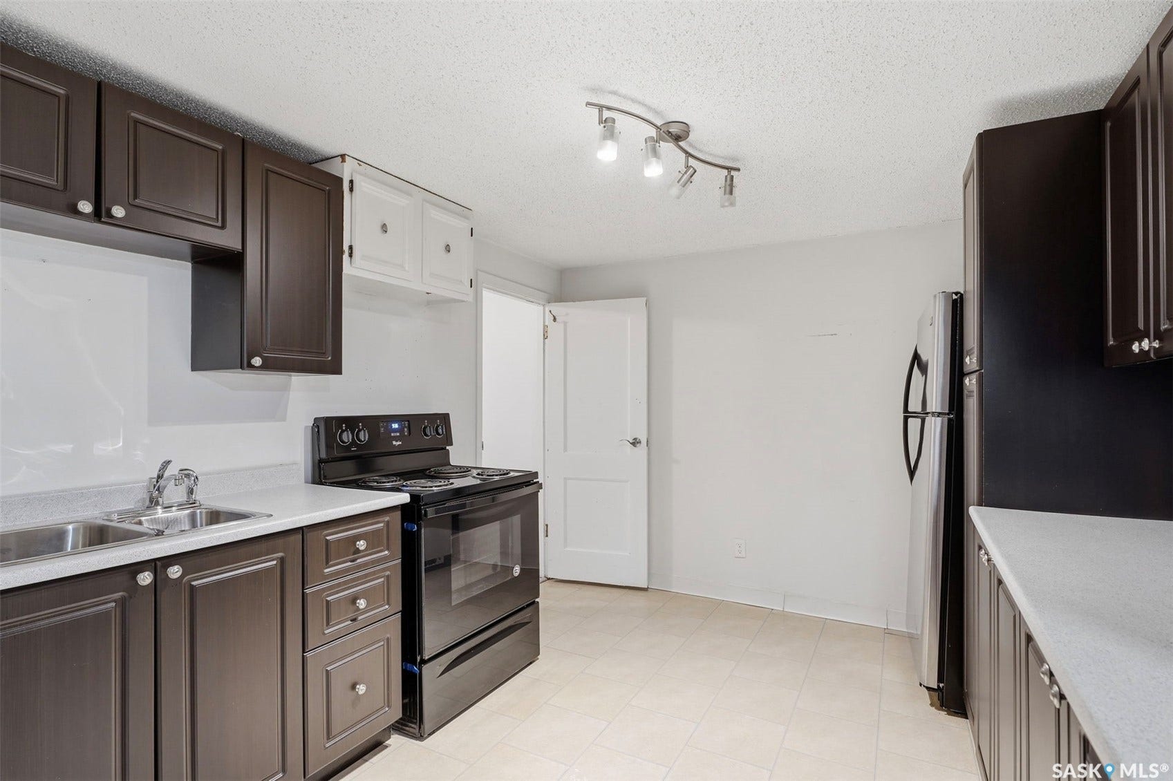 Kitchen featuring dark wood-finish cabinetry, light countertops, and a track lighting fixture