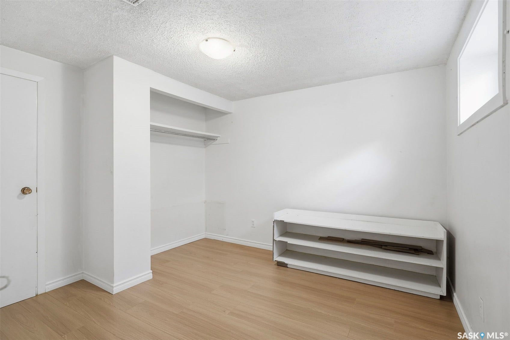 Light wood-finish flooring, built-in closet shelving, and a single window