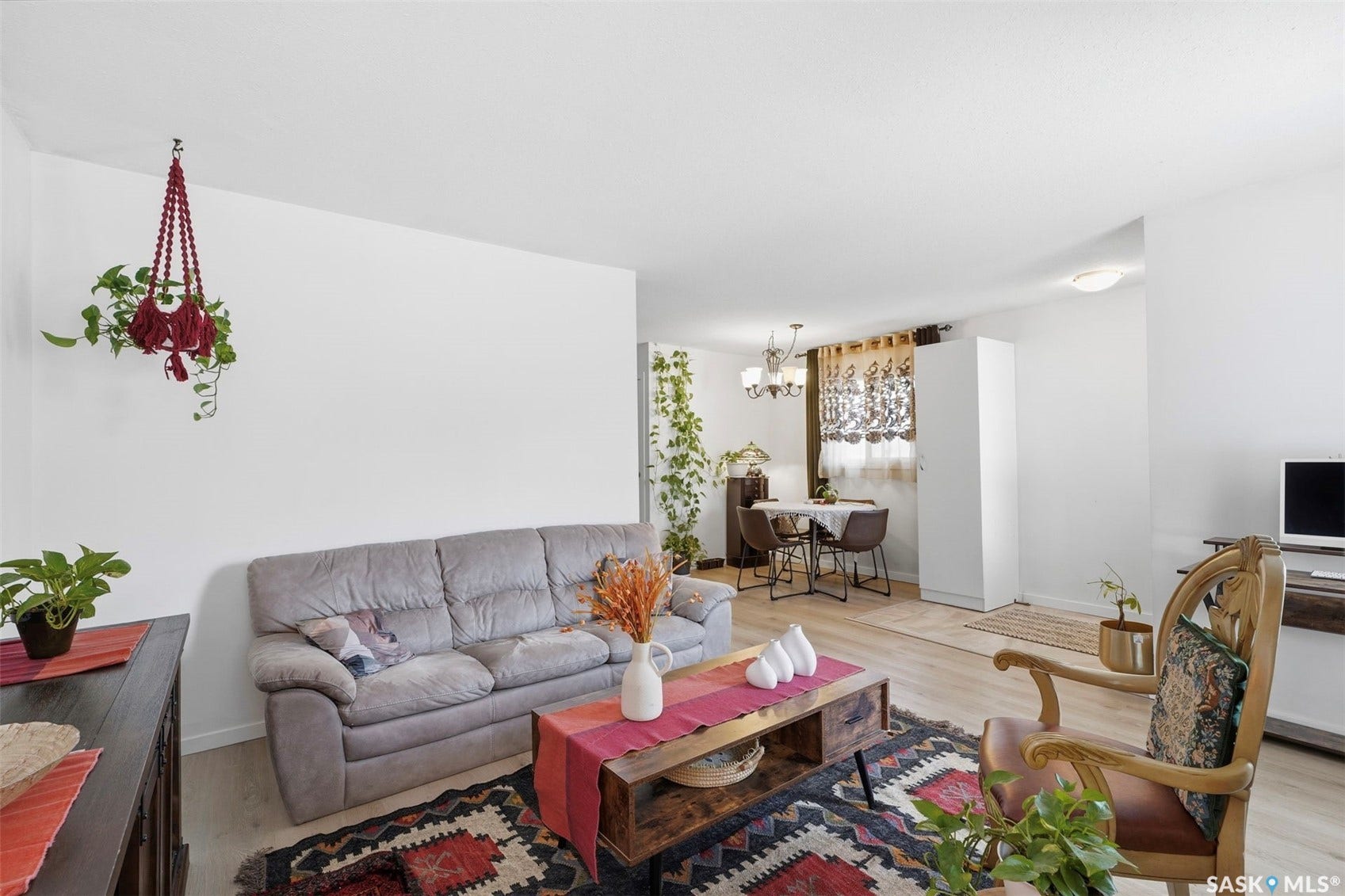 Light wood-finish flooring throughout, white walls, and an overhead light fixture in the dining area