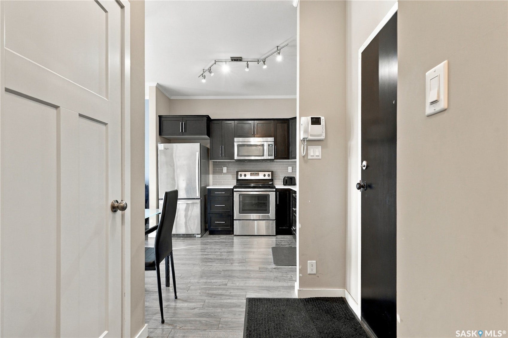Kitchen featuring dark wood cabinetry, stainless steel appliances, and a tiled backsplash