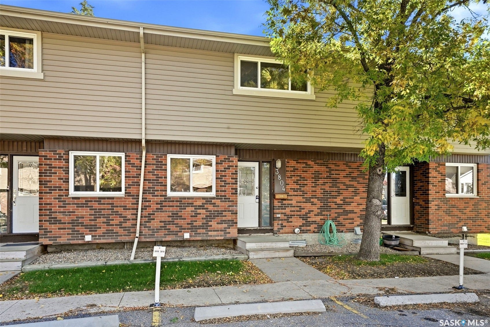 Brick and siding exterior with mature landscaping and white-framed windows