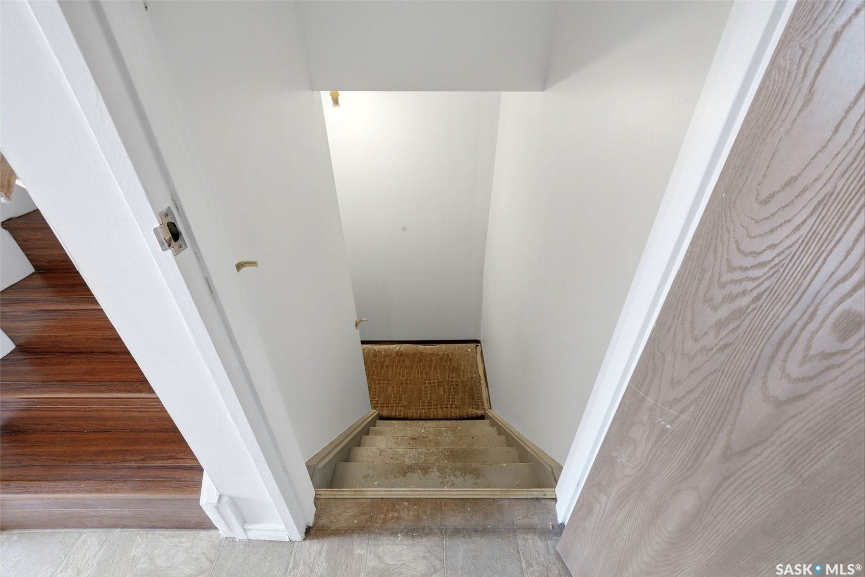 White painted walls, wood-finish flooring, and a descending staircase