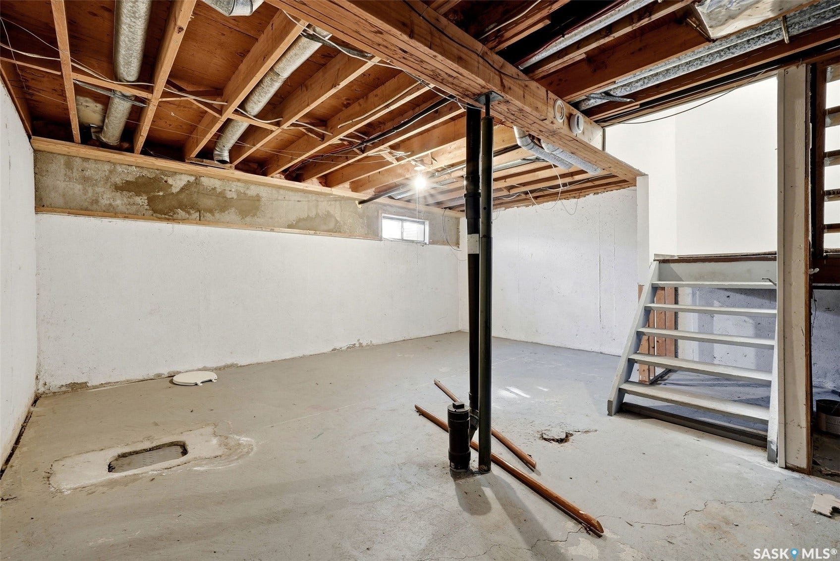 Unfinished lower level with exposed wood joists and concrete flooring