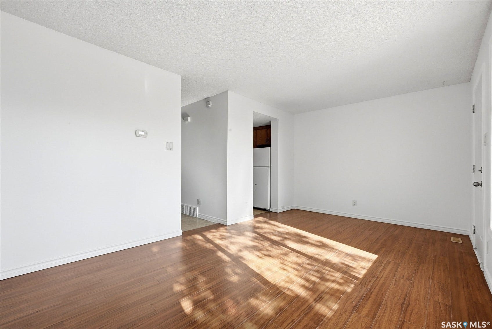 Wood-finish flooring, white walls, and a textured white ceiling