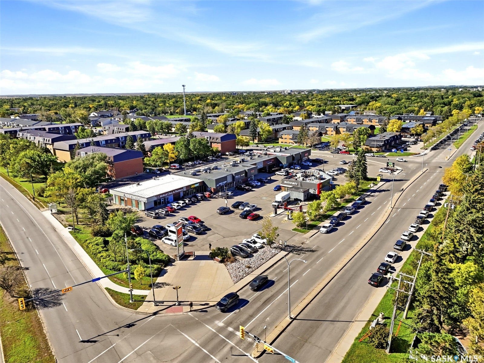Commercial property with extensive parking, surrounded by mature trees and residential developments