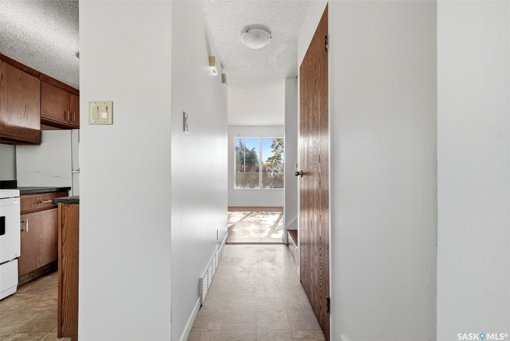 Hallway with light-colored flooring, white walls, and track lighting