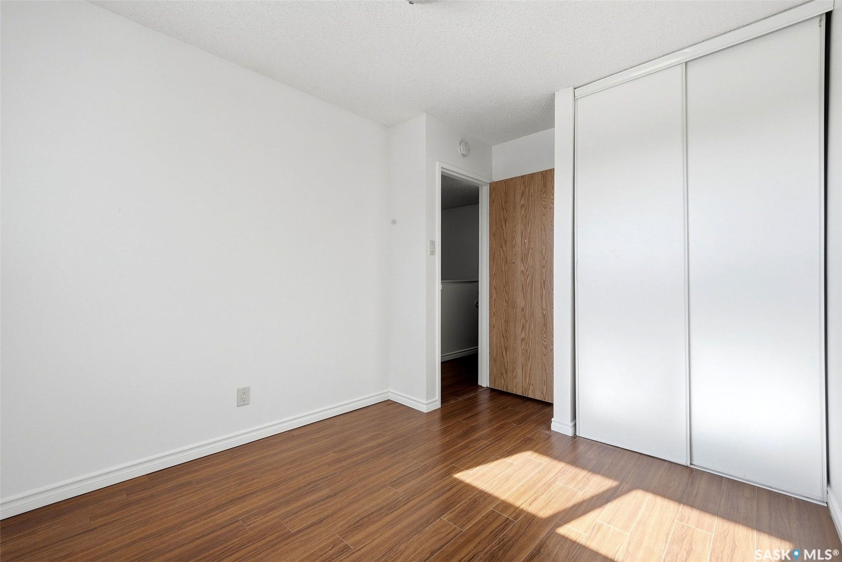 Wood-finish flooring, white walls, and a built-in closet with sliding doors