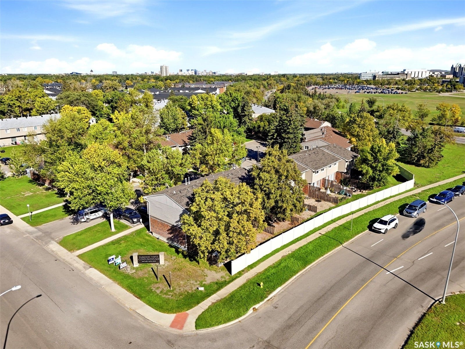 Gabled roofline, brick and siding exterior, fenced perimeter, adjacent paved road, and established trees