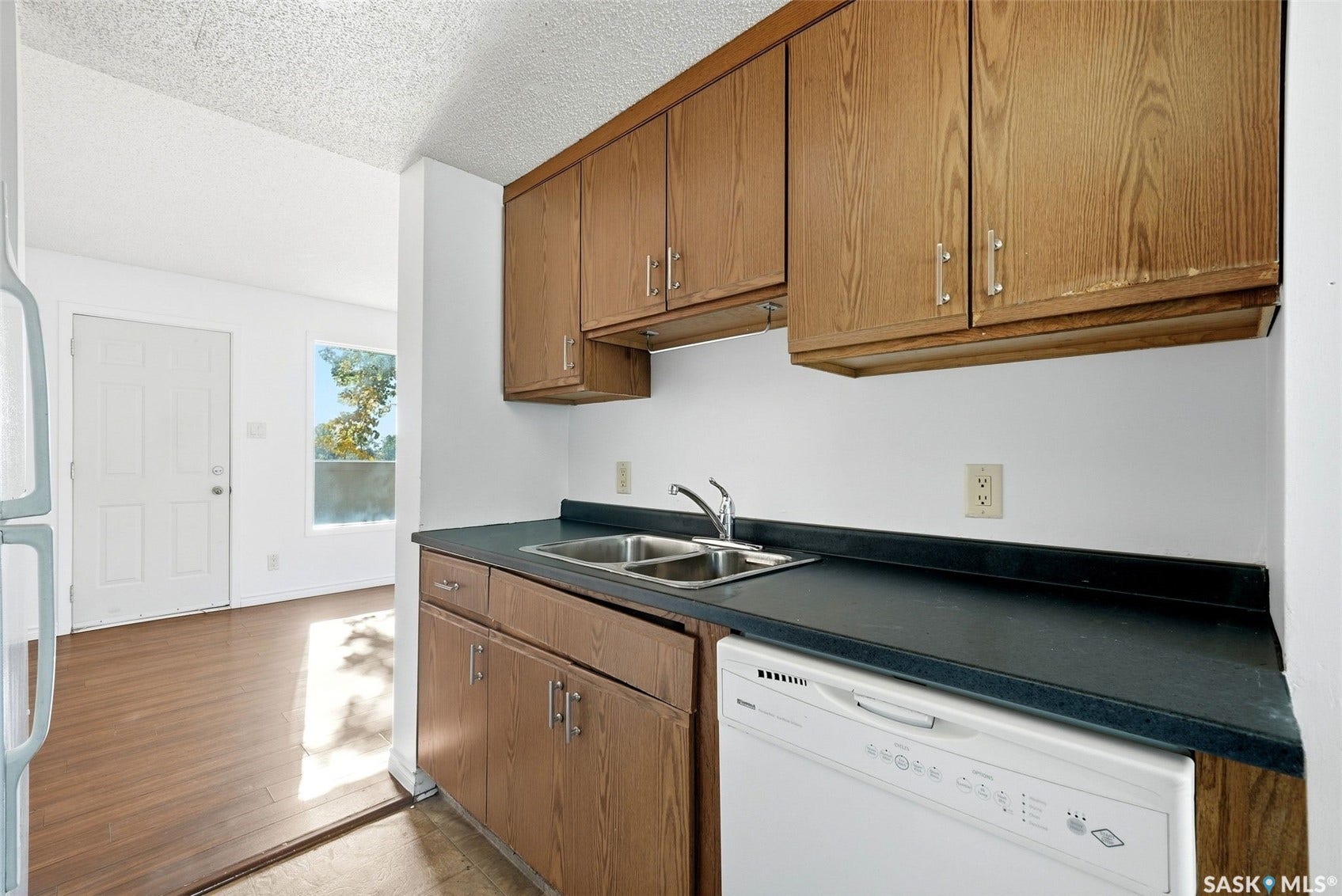 Kitchen with wood-finish cabinetry, dark countertops, and a double basin stainless steel sink