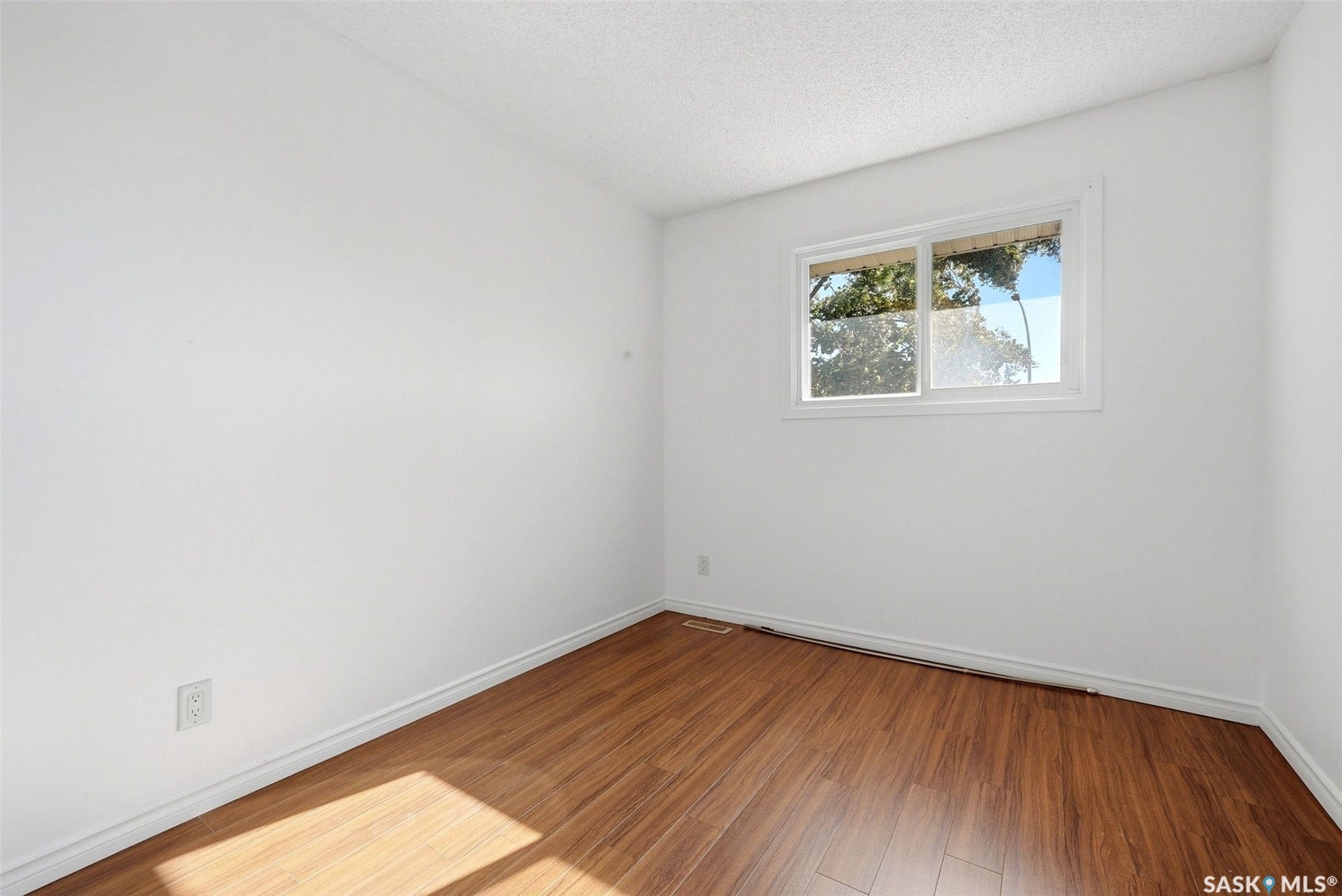 Wood-finish flooring, white walls, and a window with white trim