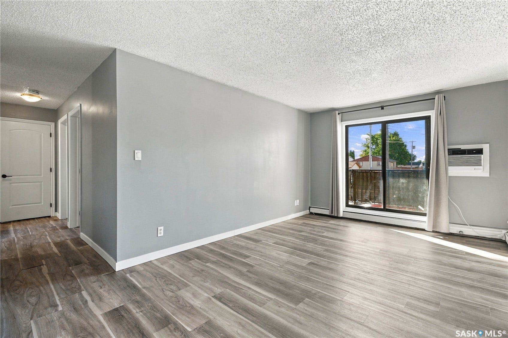 Wood-finish flooring throughout, light gray wall paint, and a sliding glass door