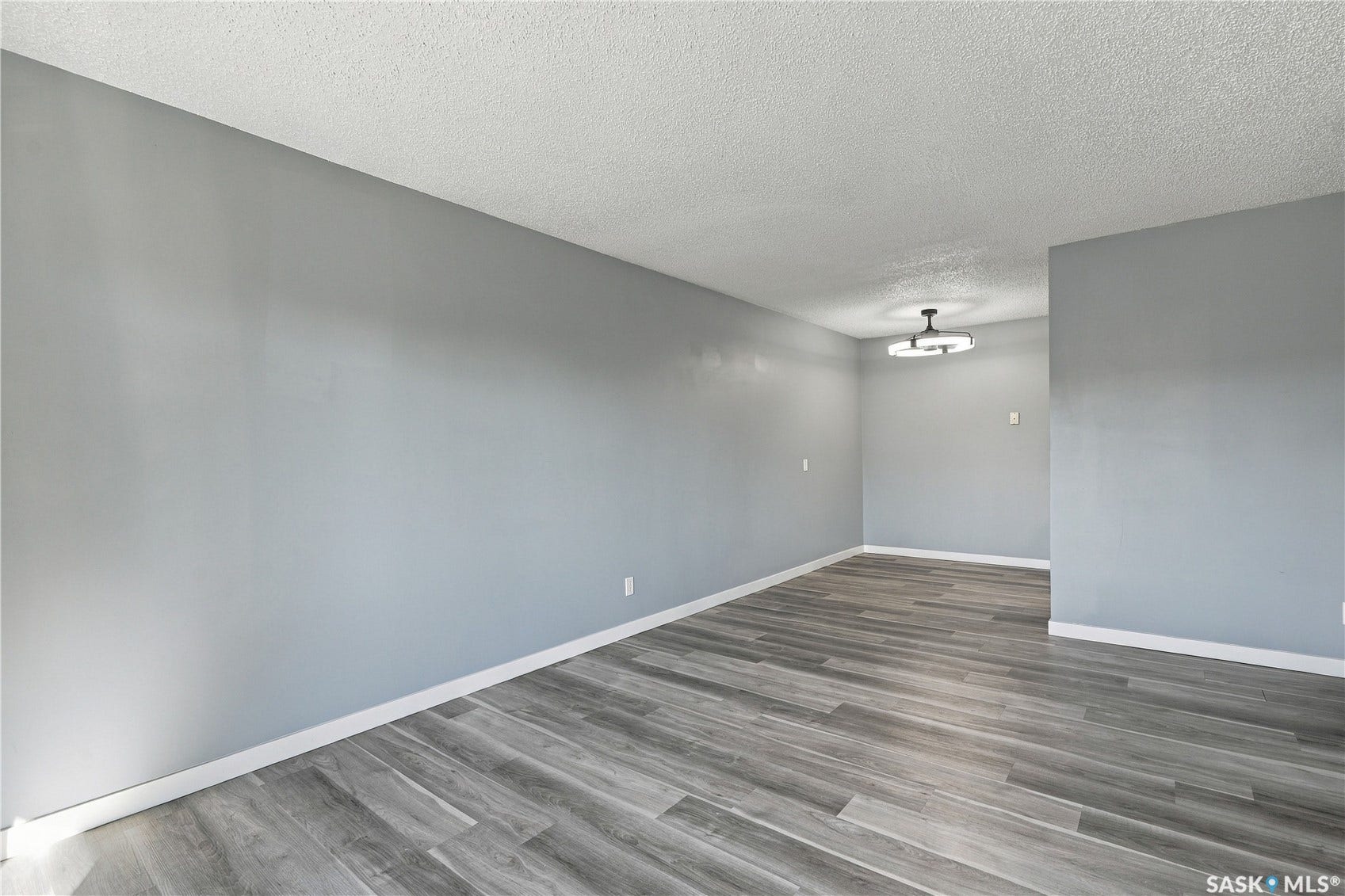Wood-finish flooring, light gray wall color, textured ceiling, and a modern ceiling fixture