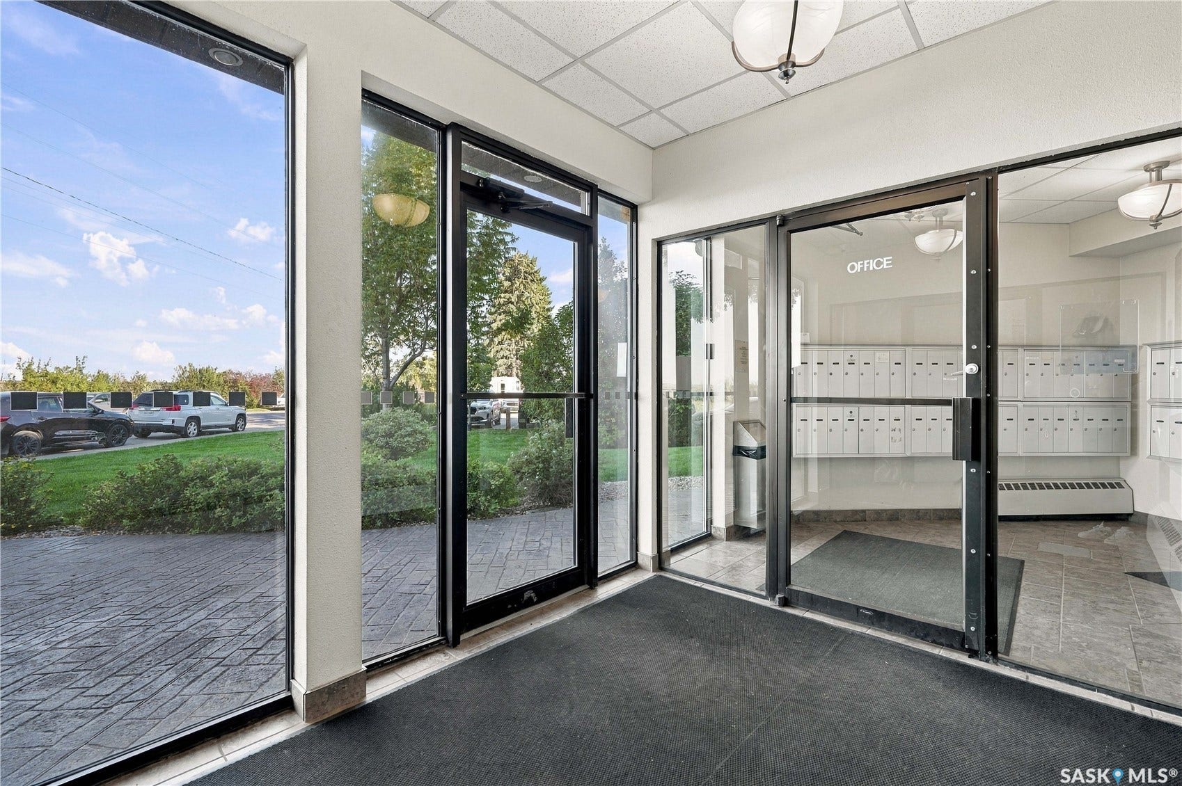 Entryway featuring large glass panels, a tiled floor, and a wall of mailboxes