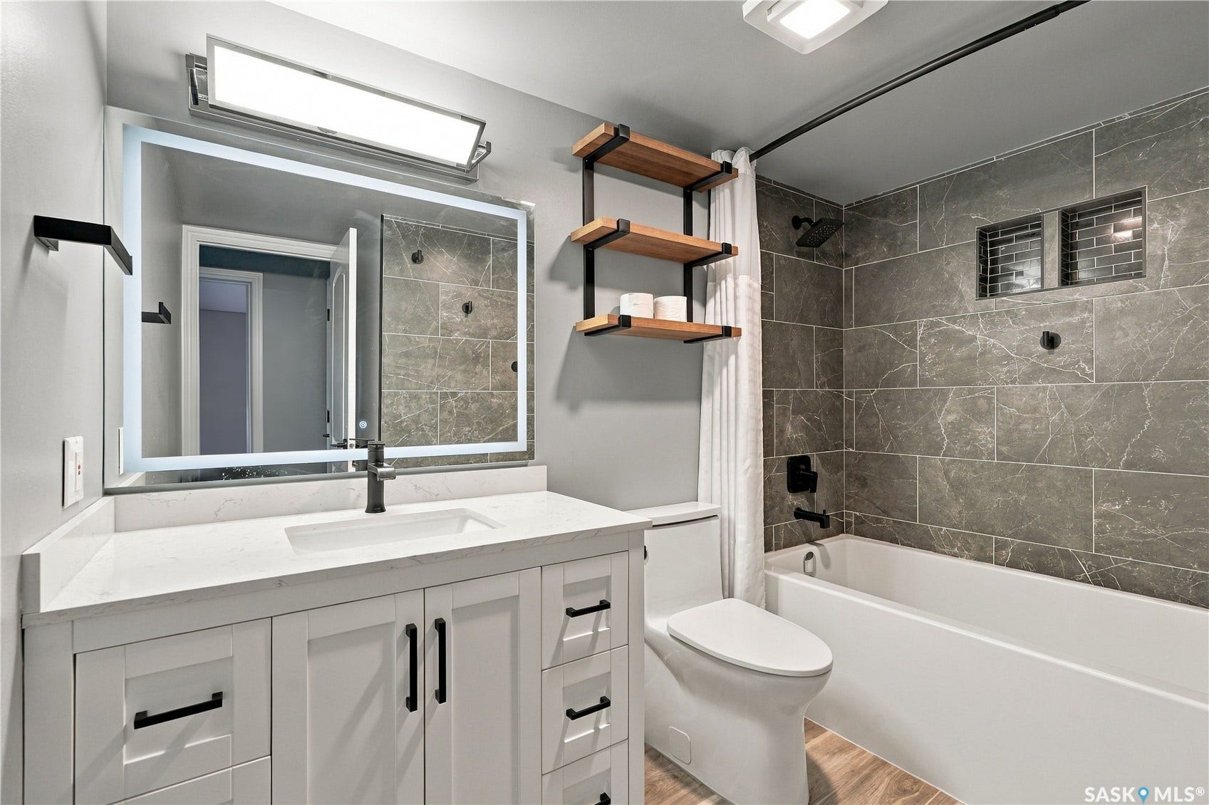 Vanity with white shaker cabinetry, integrated sink, and illuminated mirror