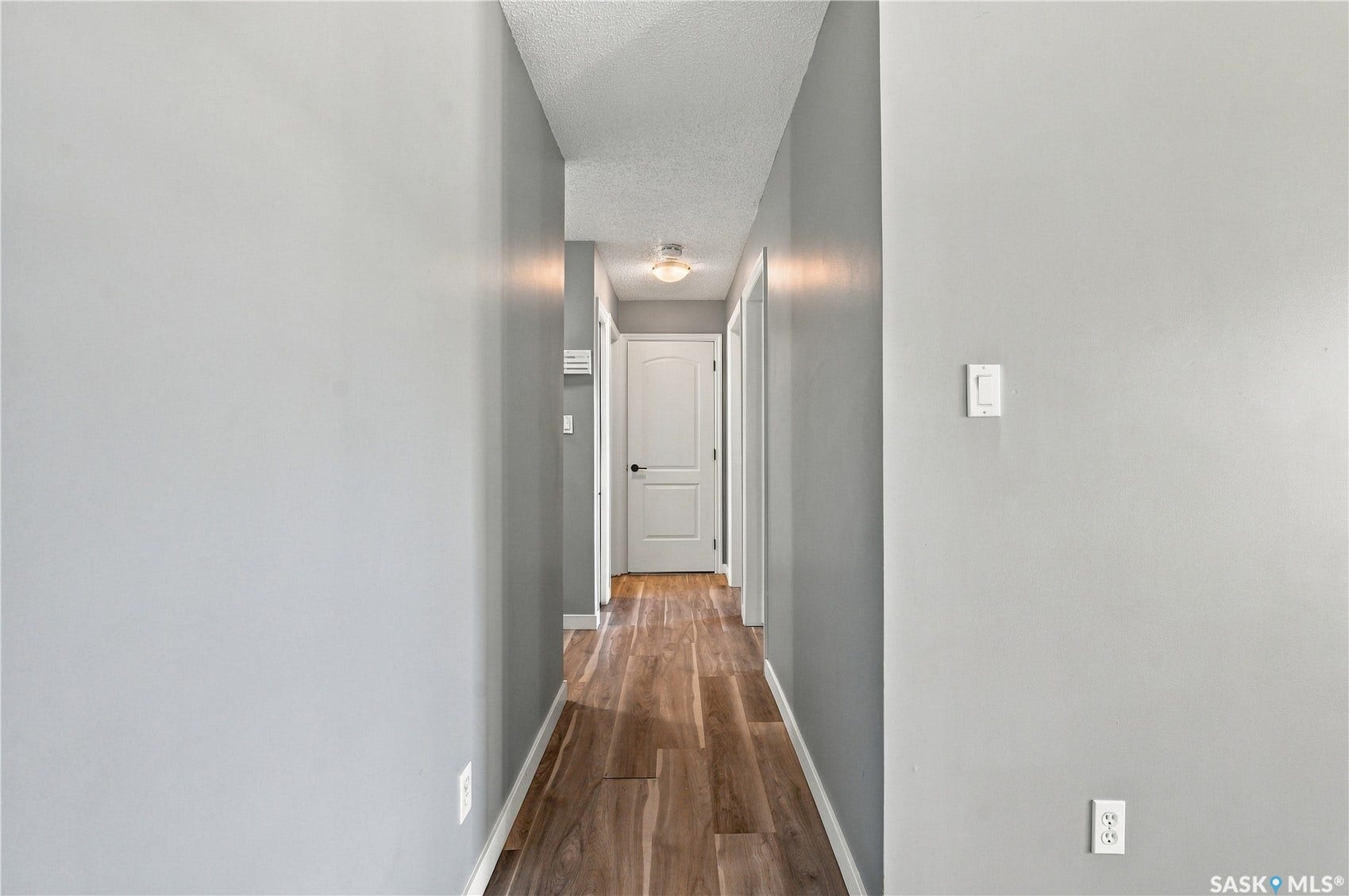 Hallway featuring wood-finish flooring, light grey walls, and a recessed ceiling light