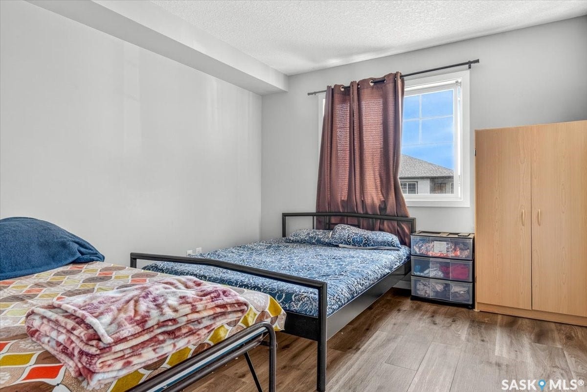 5051 James Hill Road, #107, Regina SK S4W 0B9 Wood-finish flooring, white painted walls, large window with natural light, built-in wardrobe