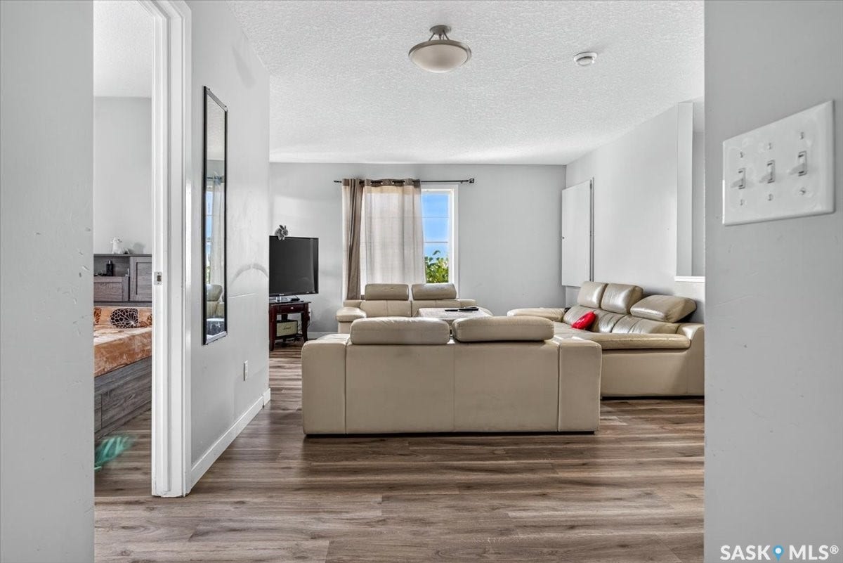 5051 James Hill Road, #107, Regina SK S4W 0B9 Wood-finish flooring throughout, light gray wall finishes, and a single window with drapes