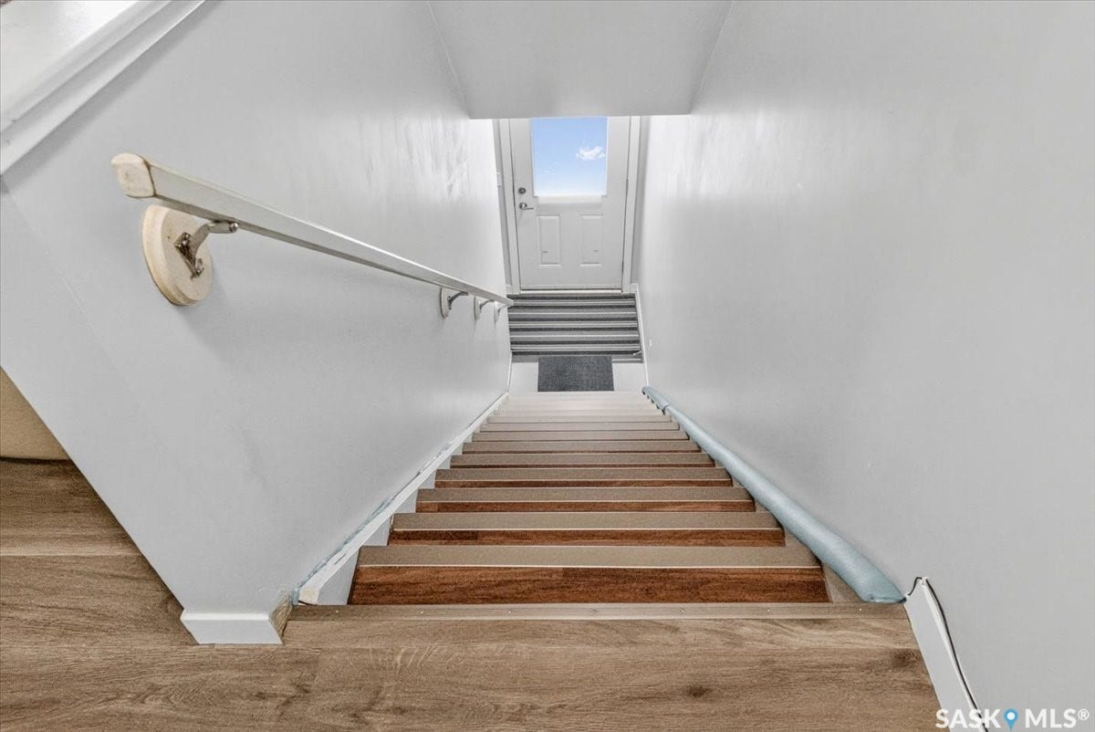 5051 James Hill Road, #107, Regina SK S4W 0B9 Staircase with wood-finish treads, white risers, and a wall-mounted handrail