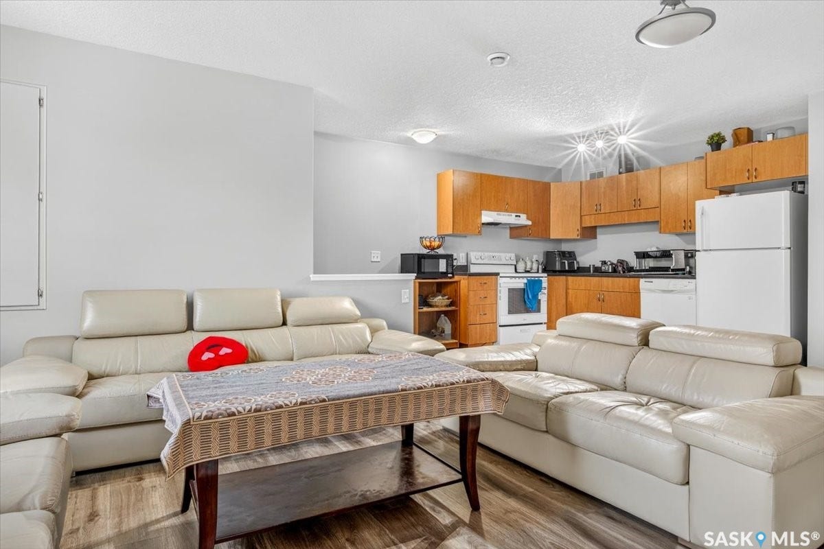 5051 James Hill Road, #107, Regina SK S4W 0B9 Wood-finish flooring throughout, light gray wall finishes, recessed lighting, wood cabinetry, and white appliances