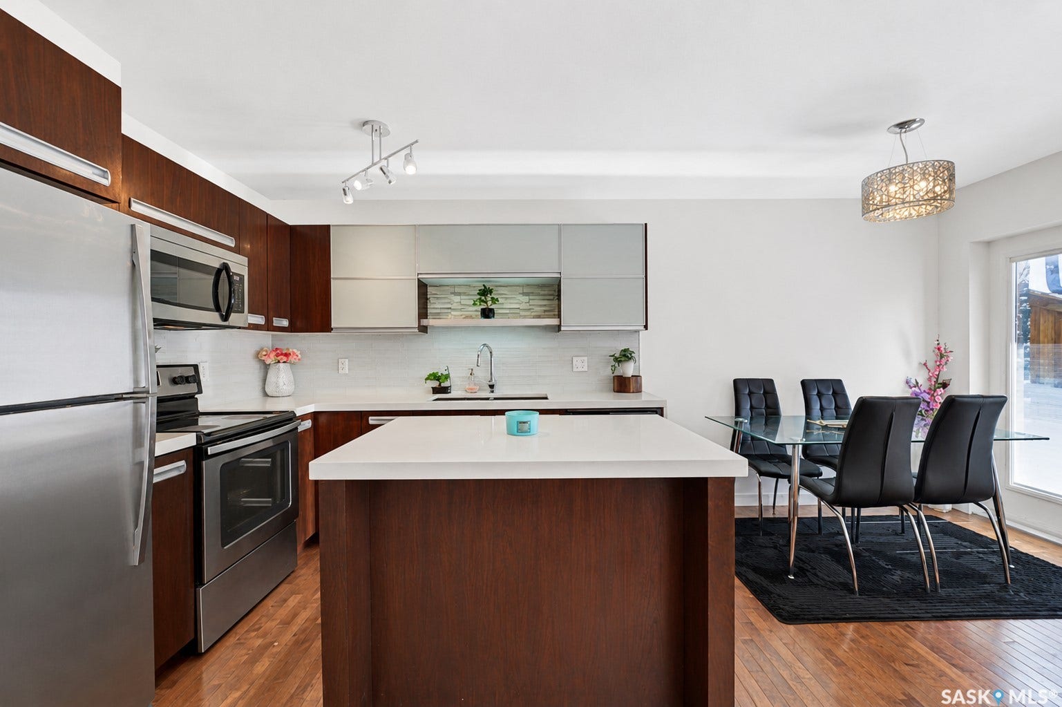 Kitchen featuring wood-finish cabinetry, stainless steel appliances, a center island with a white countertop, and wood-finish flooring