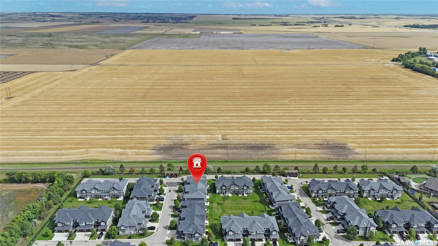 Aerial perspective of a developed residential community bordered by expansive agricultural fields