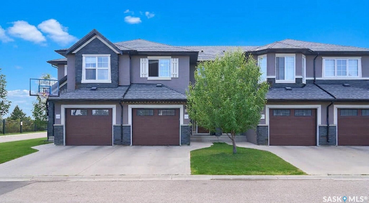 Multi-unit dwelling featuring a composite shingle roof, stone accents, multiple bay windows, and attached garages with panel doors