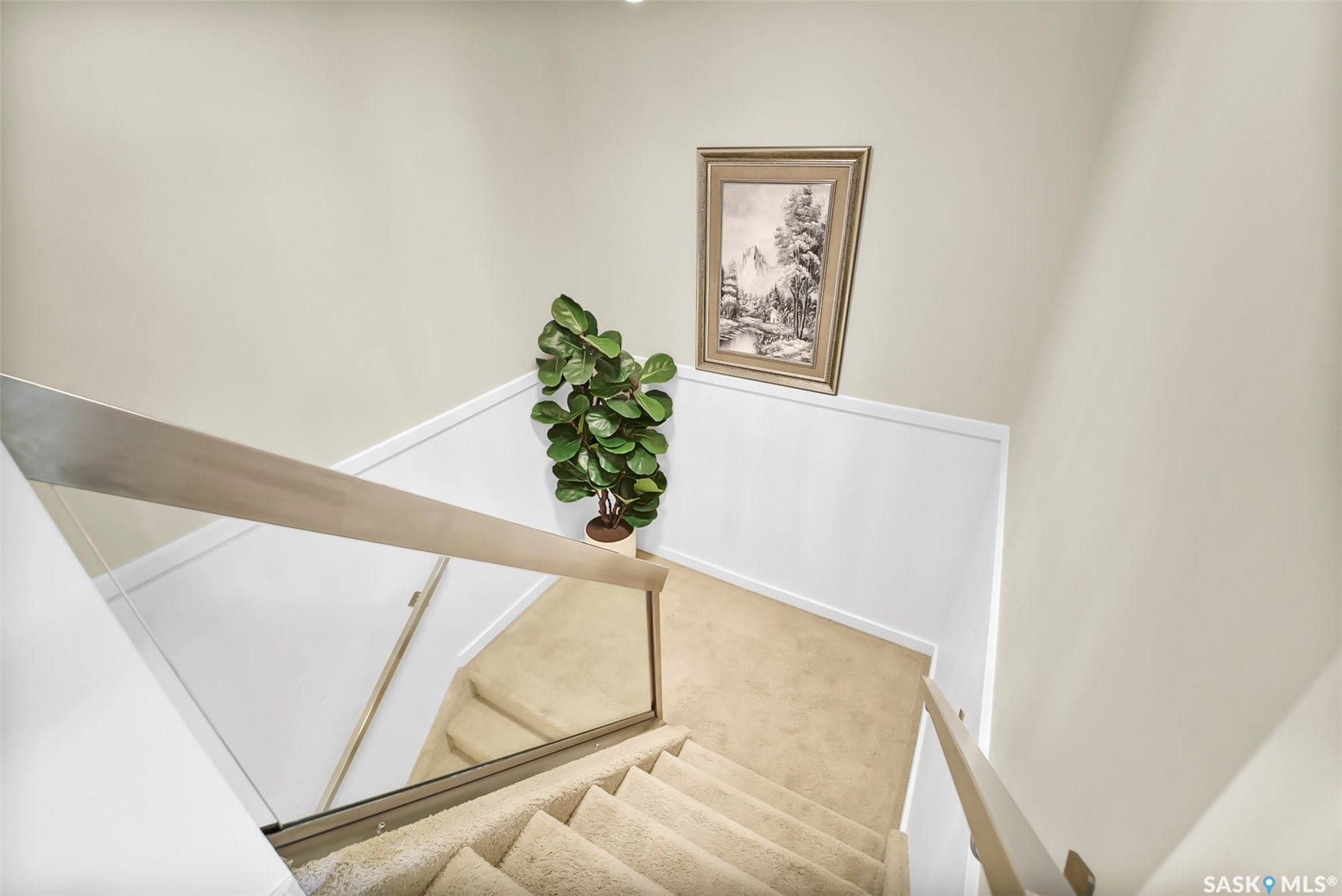 Carpeted staircase with glass and wood-finish railings, neutral wall paint, and white trim