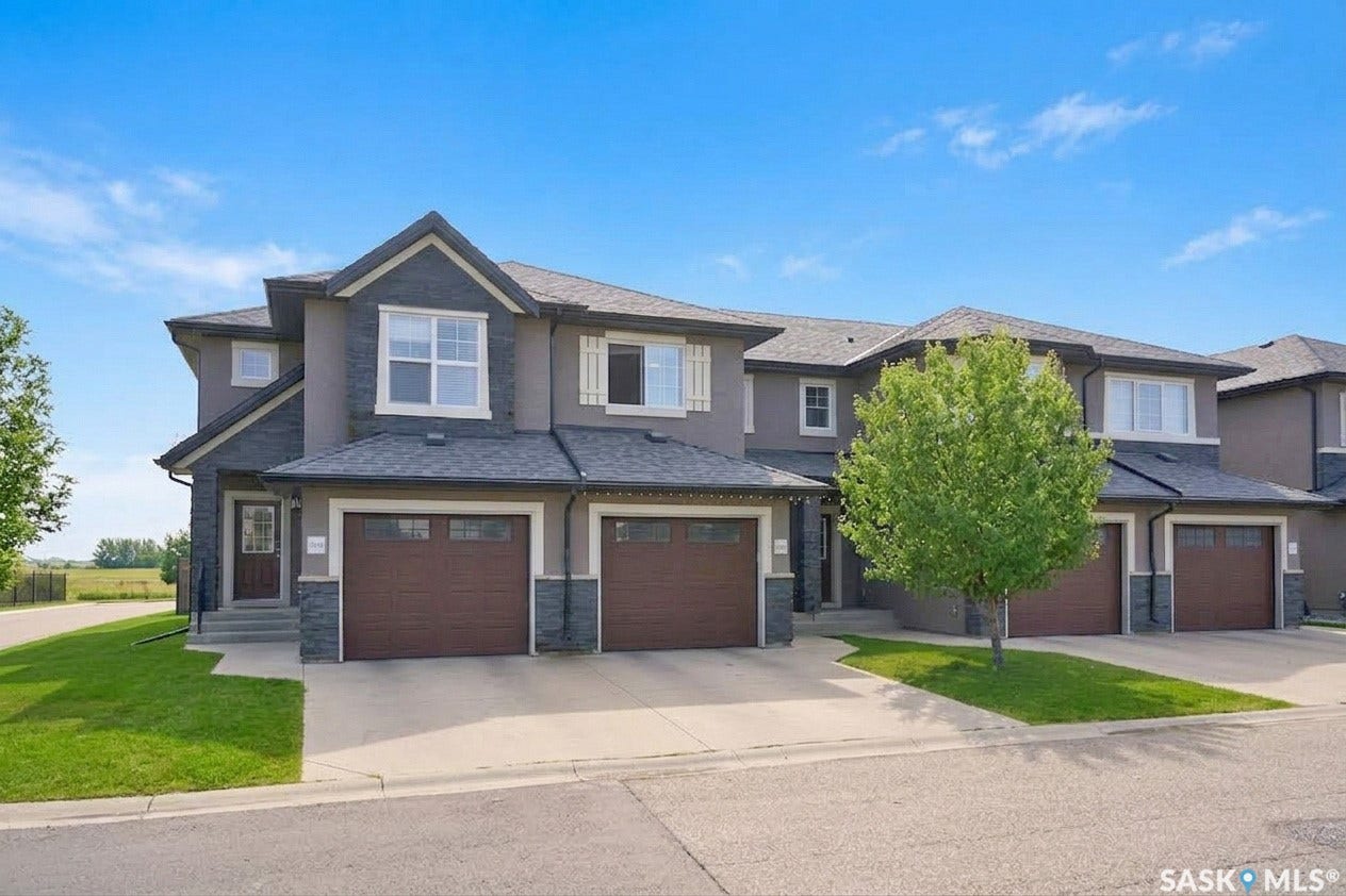Townhome exterior featuring stone accents, stucco siding, and individual garage doors