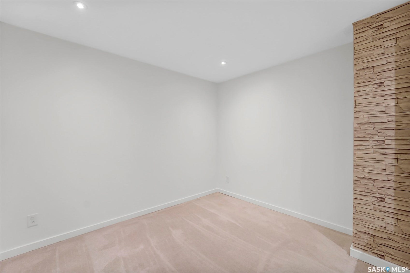 Recessed ceiling lighting, light-toned carpeting, white walls, and a stacked stone accent wall