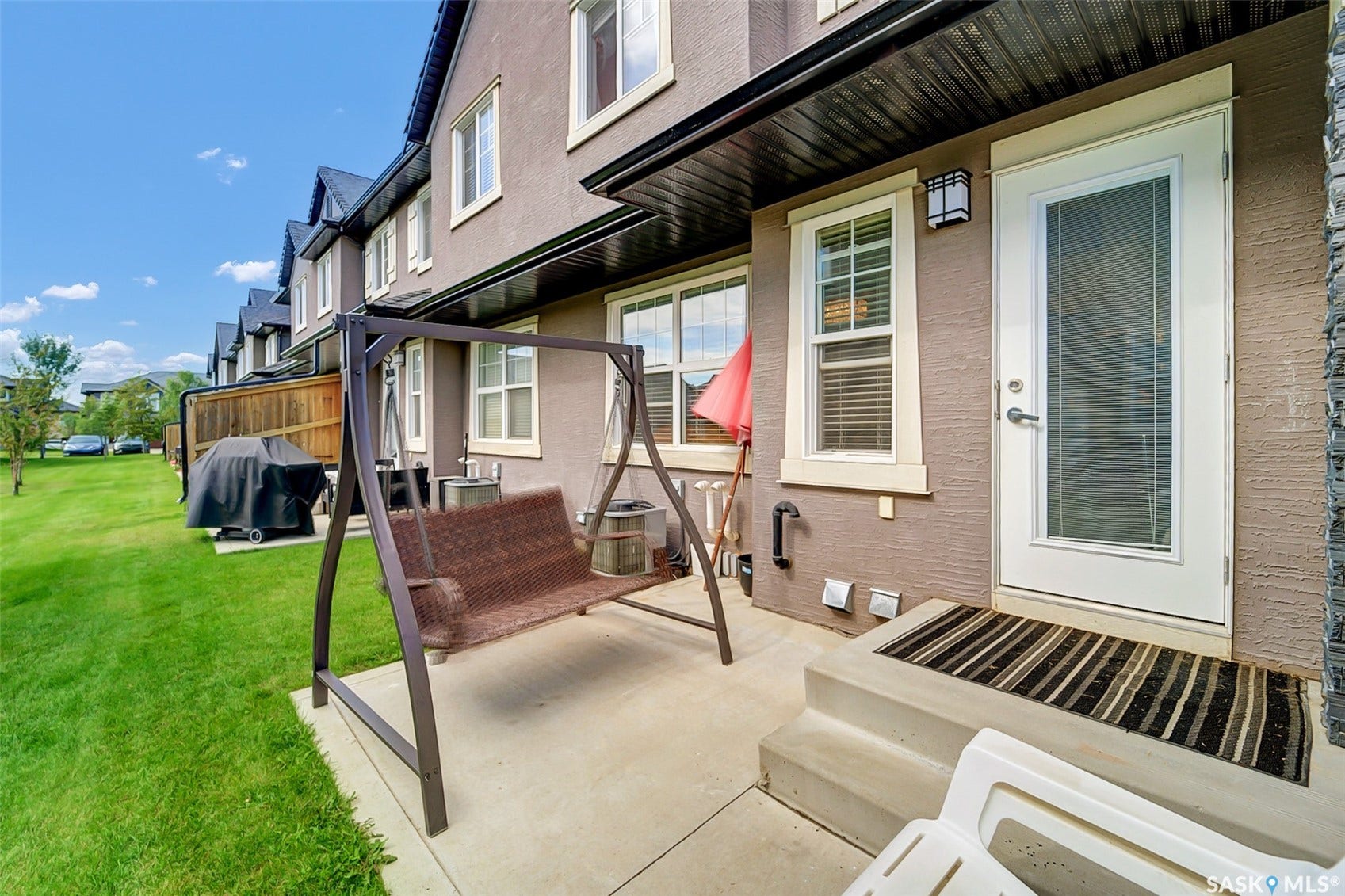 Paved patio with direct outdoor access, featuring a stucco exterior and white-trimmed windows