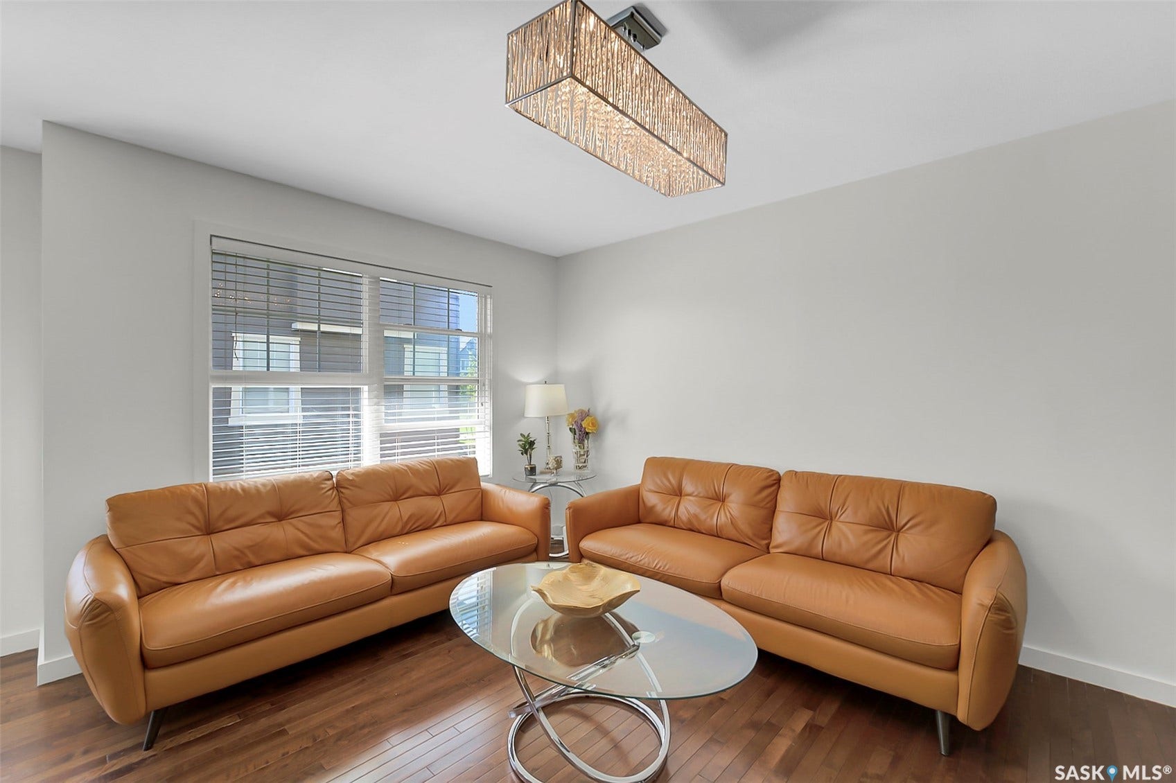 Recessed window with horizontal blinds, wood-finish flooring, and a rectangular crystal chandelier