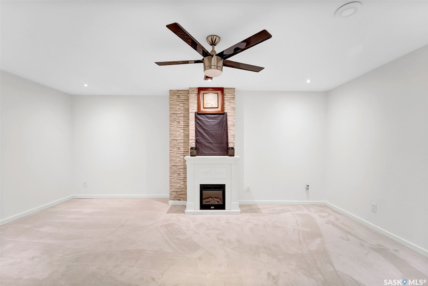 Stone-faced fireplace with a white mantel, recessed lighting, and a ceiling fan