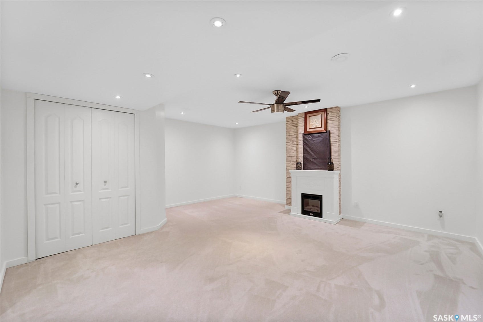Recessed lighting, ceiling fan, fireplace with stone surround, built-in bi-fold closet doors, and light-colored carpeting