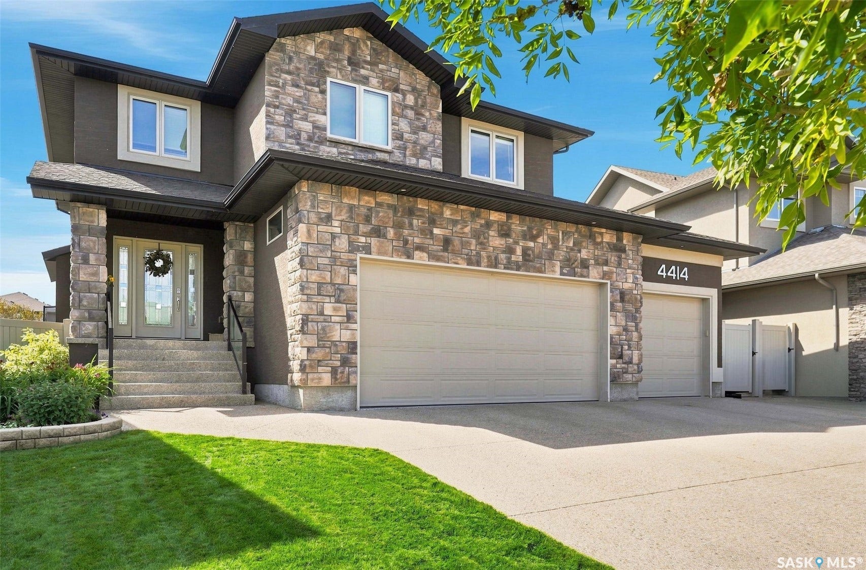 4414 Sandpiper Crescent E, Regina SK S4V 1N3 Stone veneer and stucco exterior with multiple windows
