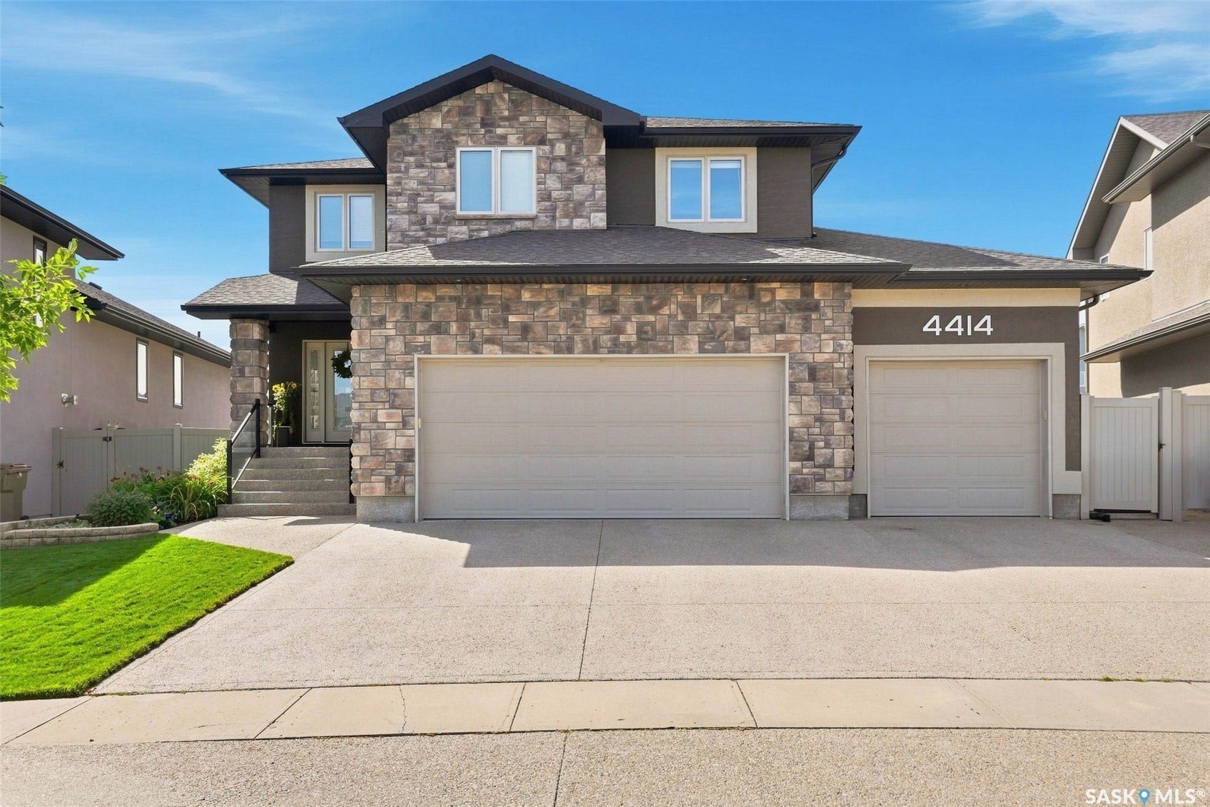 4414 Sandpiper Crescent E, Regina SK S4V 1N3 Stone facade, two-car garage, separate single-car garage, concrete driveway, and front entryway with steps