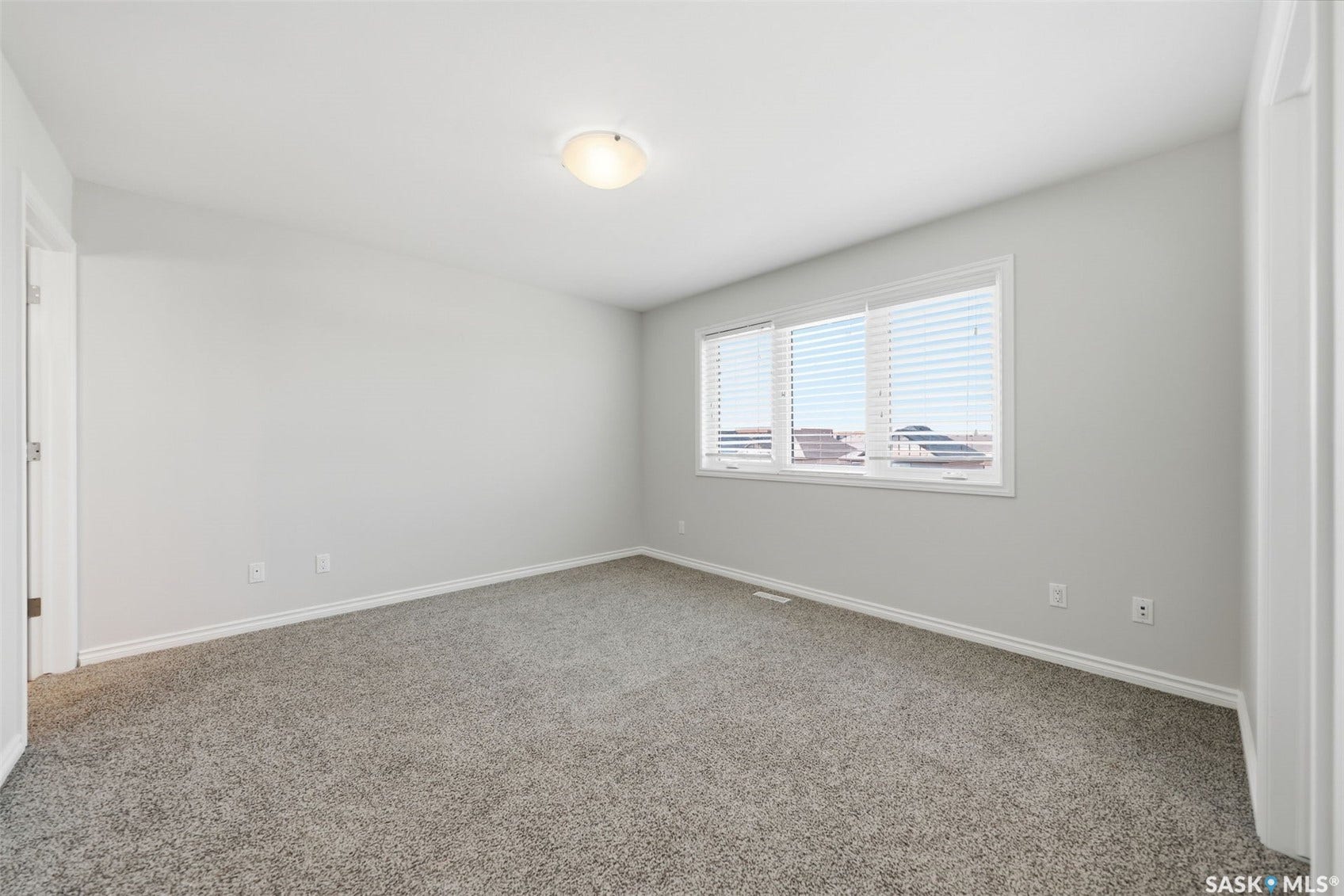 Recessed ceiling light fixture, neutral wall color, carpeted flooring, white window blinds, and white trim
