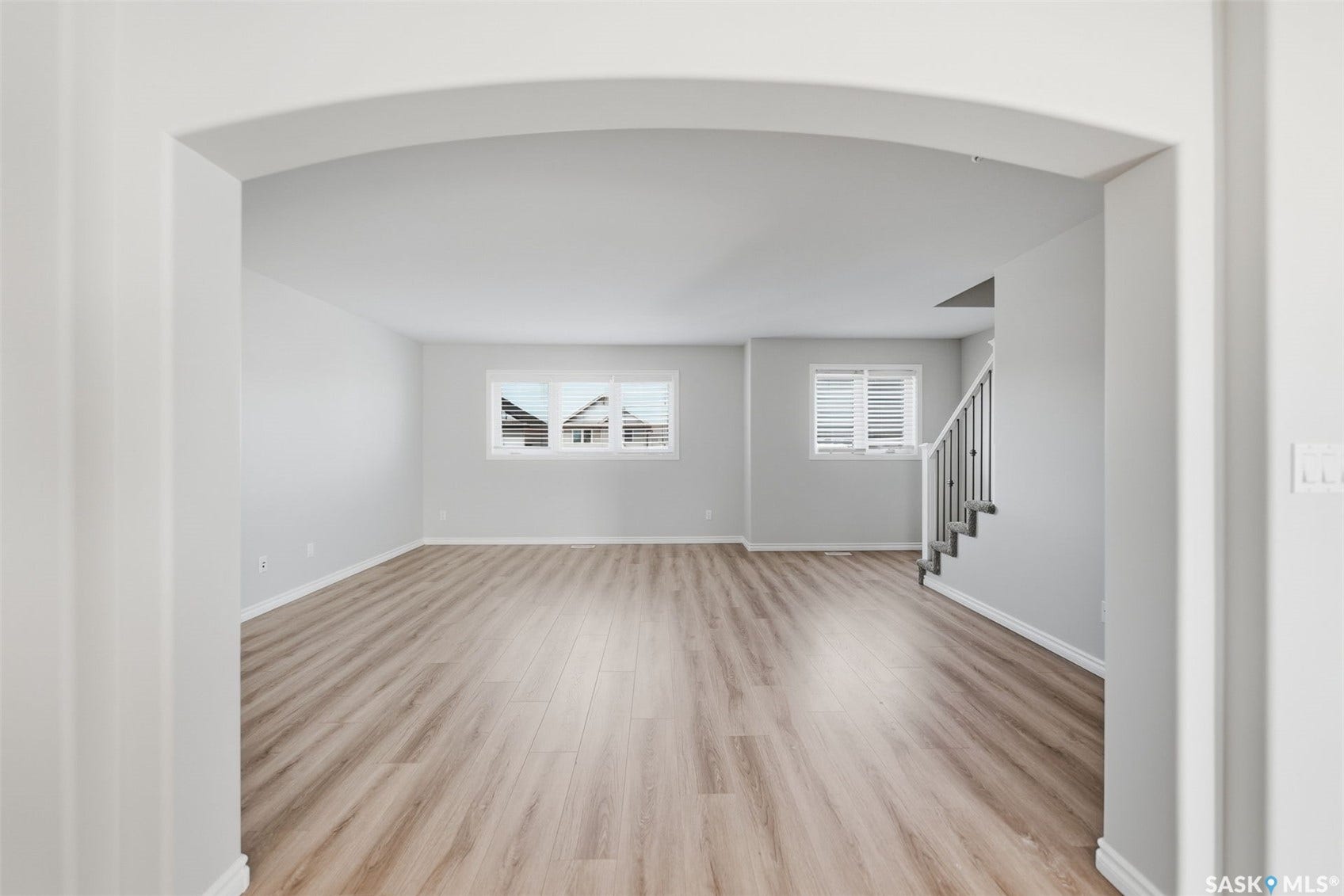 Expansive room featuring light wood-finish flooring, neutral wall tones, and multiple windows