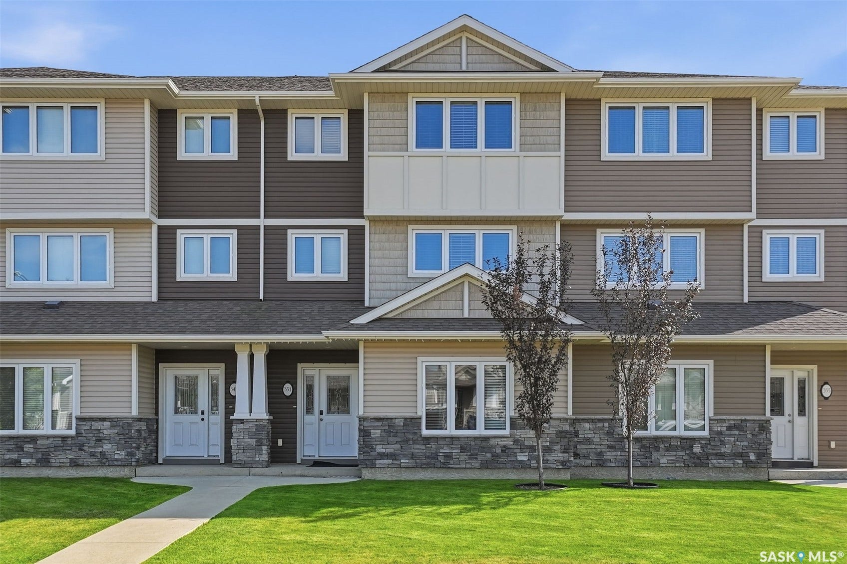 Multi-level faade with horizontal siding, stone veneer accents, and multiple windows