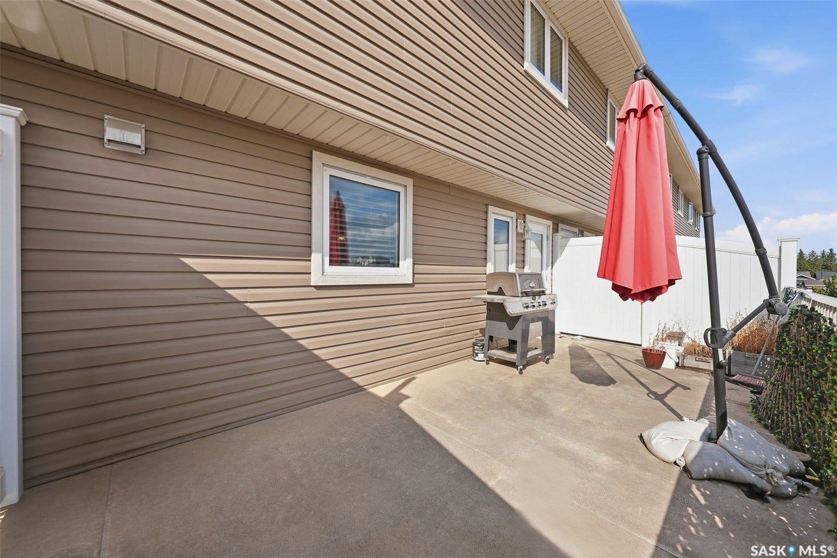 Concrete patio with light brown siding and white framed windows