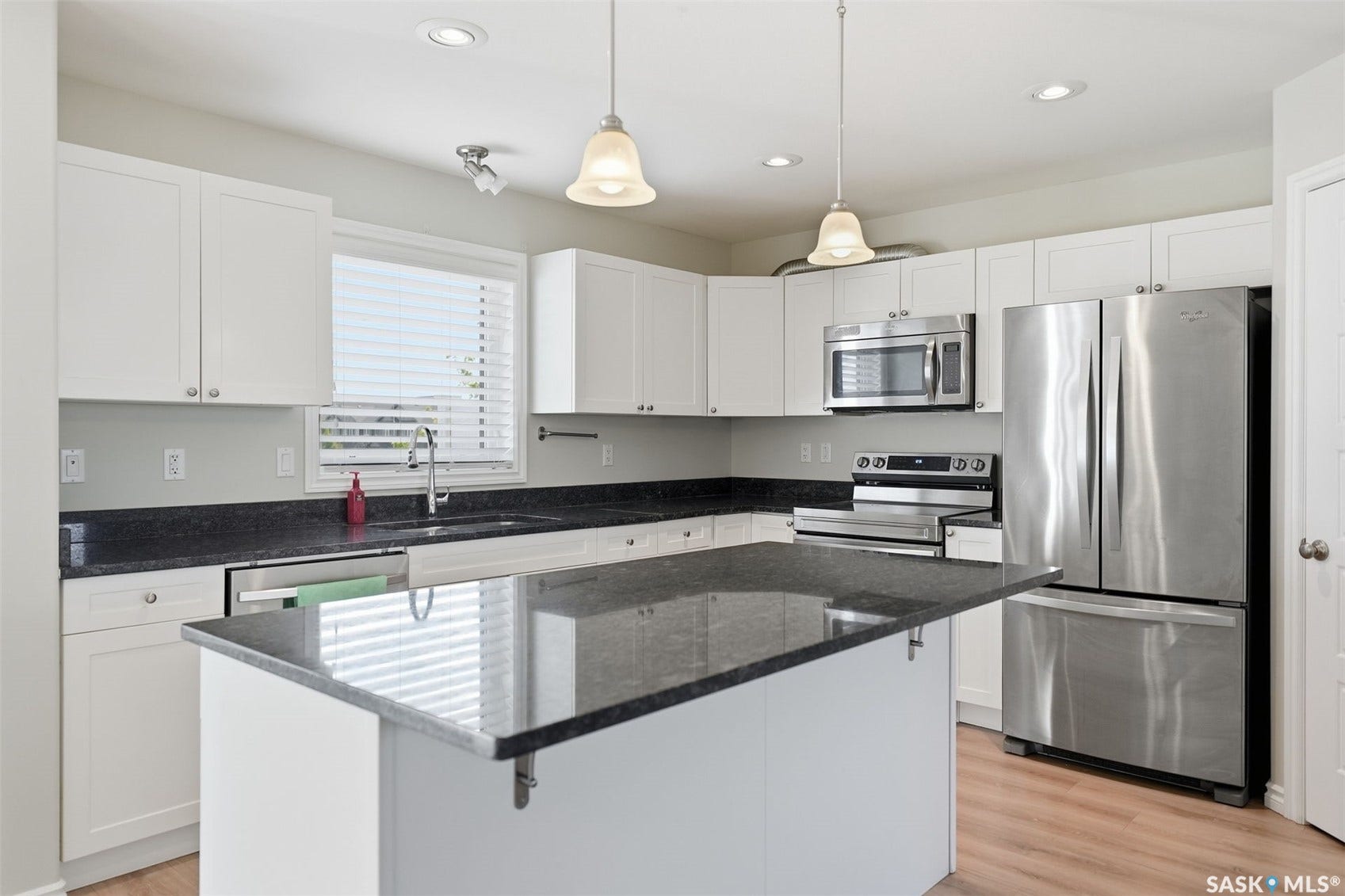 Kitchen featuring a large island, white cabinetry, dark countertops, and stainless steel appliances