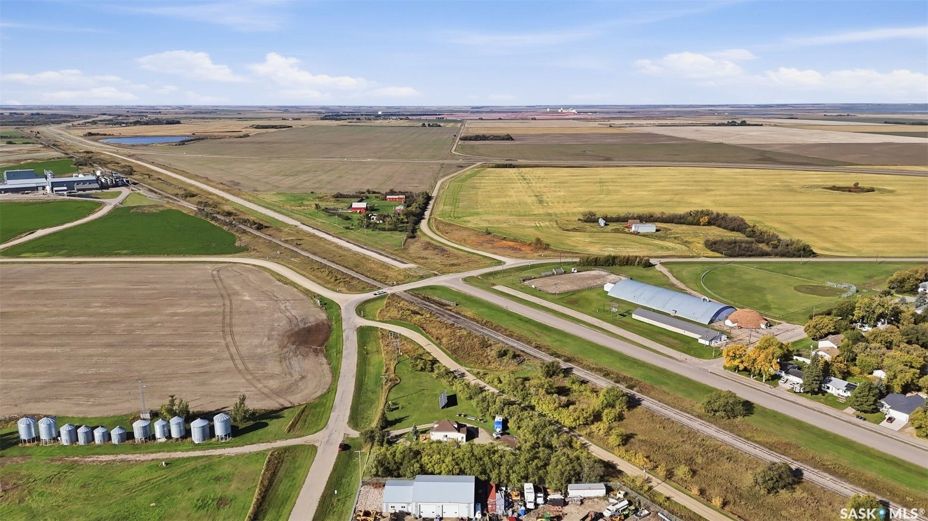 Expansive agricultural landscape featuring open fields, a body of water, and surrounding rural infrastructure