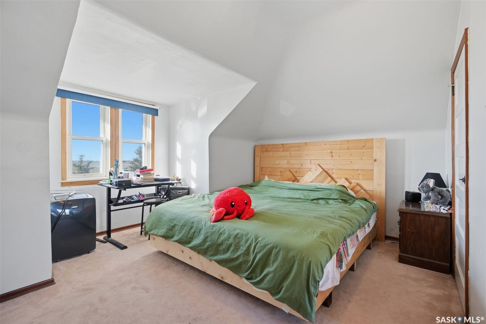 Sloped ceilings, natural wood-finish window trim, and light-toned carpeting