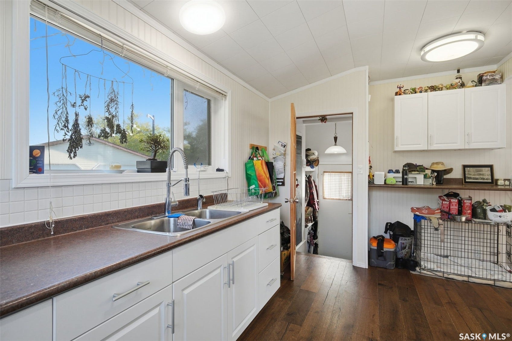 White cabinetry with stainless hardware, dual basin sink, integrated faucet, and wood-finish flooring