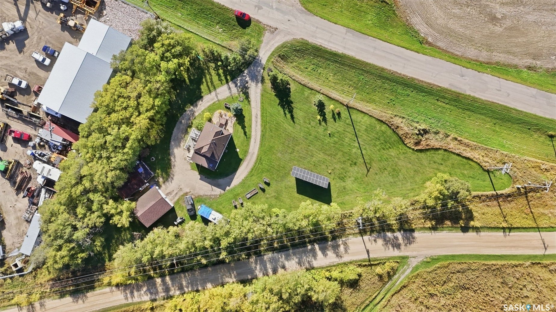 Property featuring a main residence, an outbuilding, a paved driveway, and solar panels
