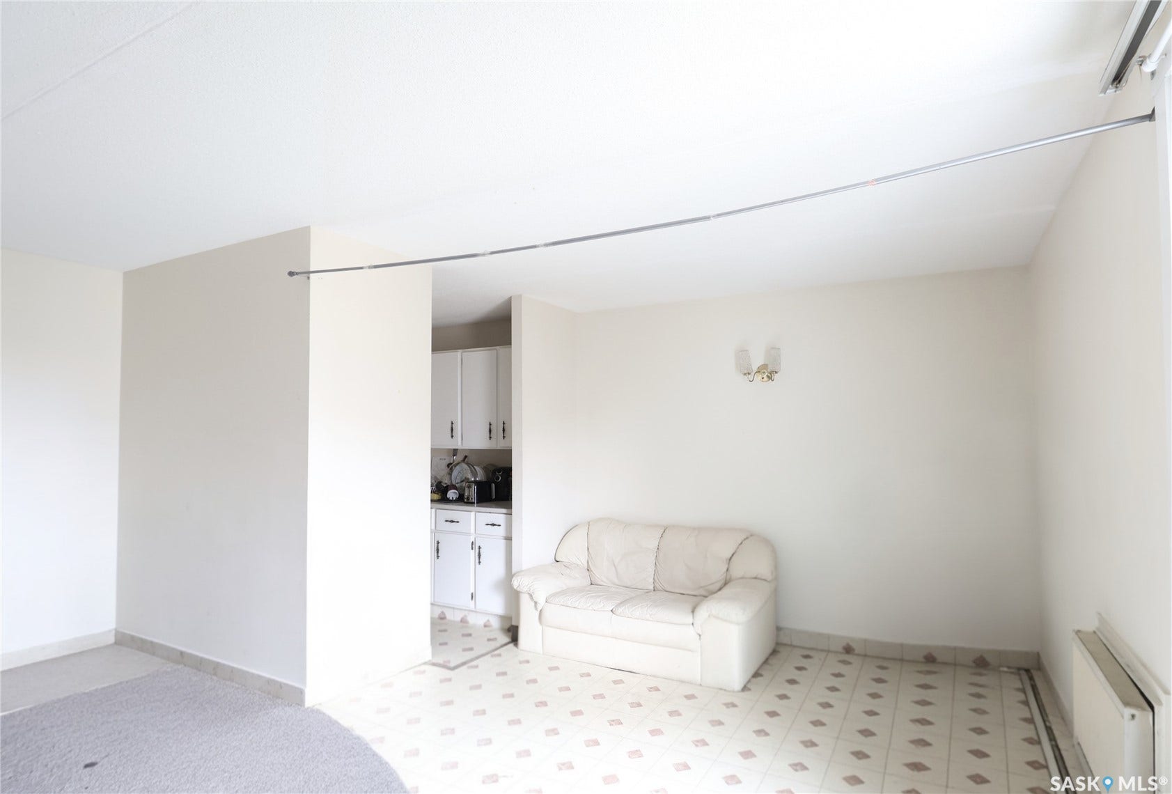 Recessed ceiling, neutral wall paint, built-in wall sconce, white cabinetry, patterned floor tiles