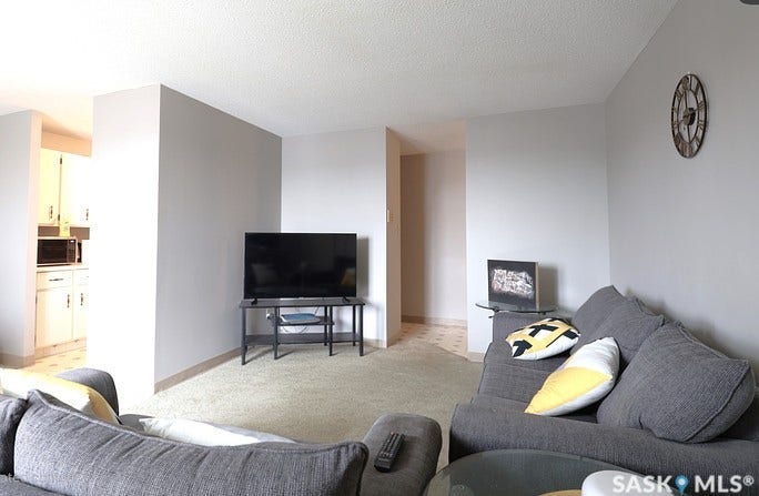 Carpeted living area with light-colored walls and a textured ceiling