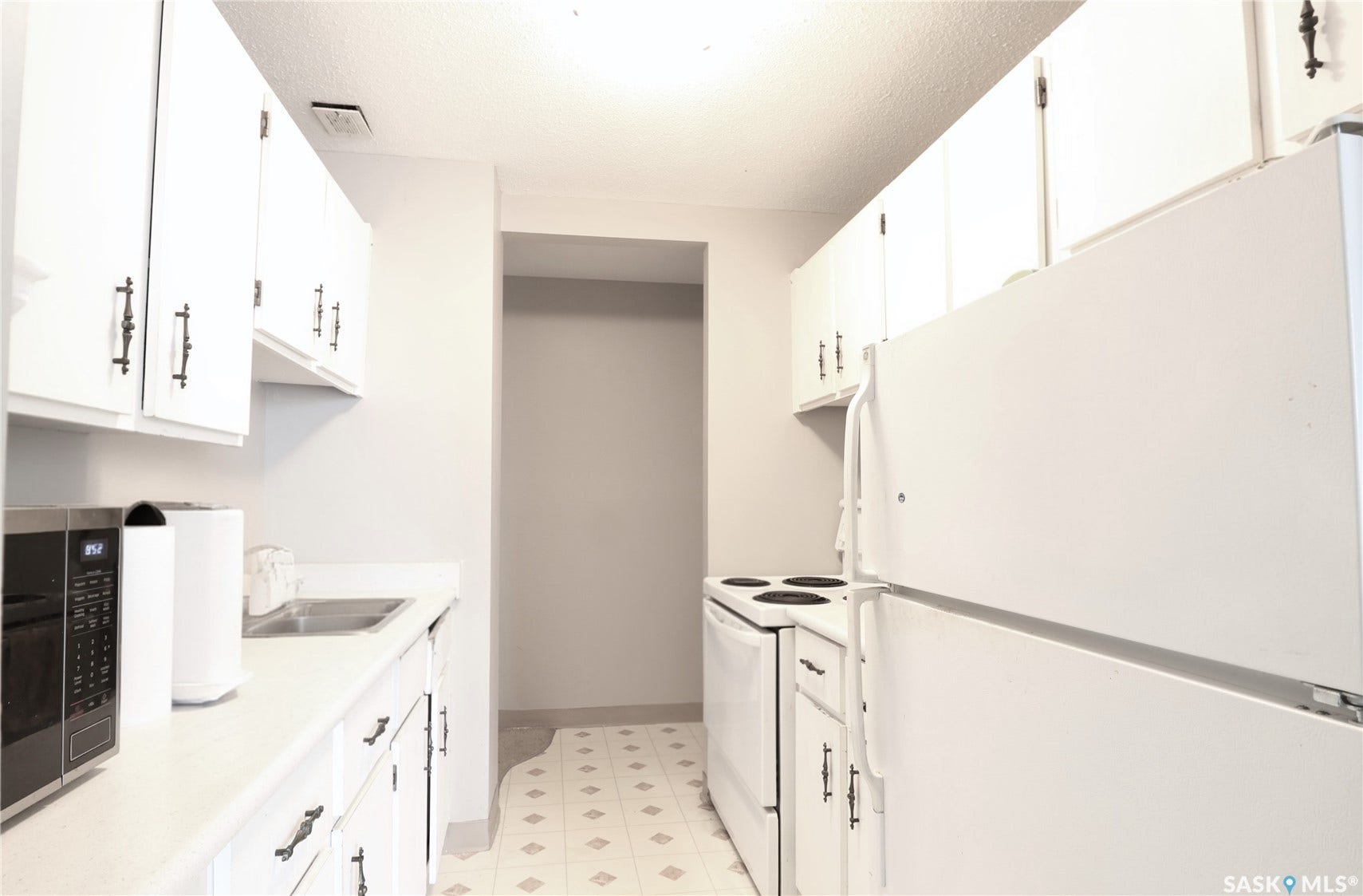Galley kitchen featuring white cabinetry with dark hardware, white countertops, white refrigerator, and white range