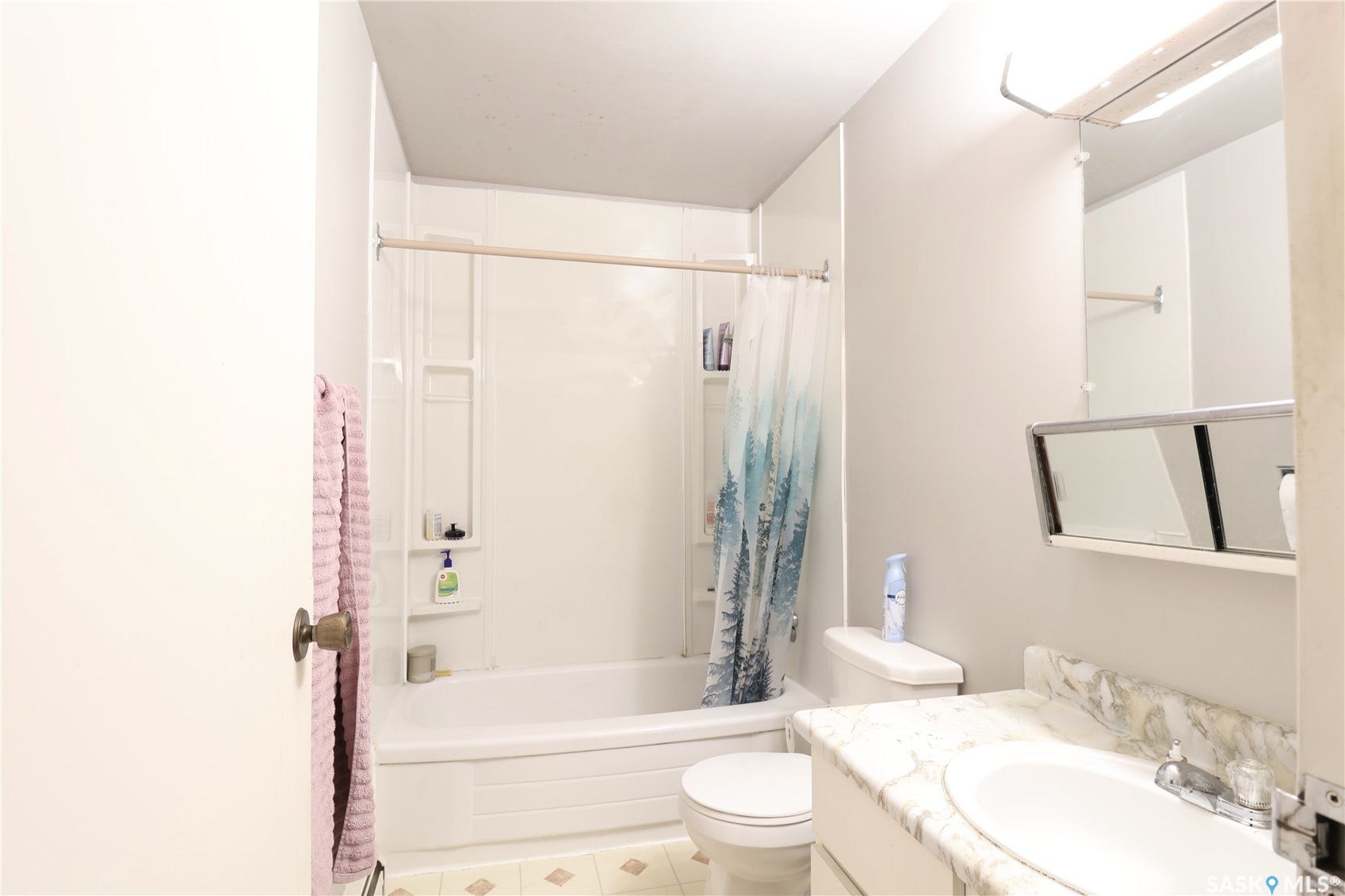 Bathroom with white bathtub/shower combination, white vanity with integrated sink, and a mirrored medicine cabinet