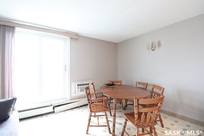 Sliding glass door, wall-mounted light fixture, patterned flooring, baseboard heating unit, wall-mounted air conditioning unit